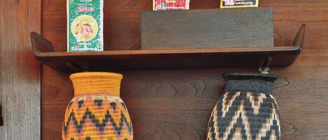 Una estantería de madera con un jarrón decorativo, dos cajas de café instantáneo y una bandeja con tazas de té.