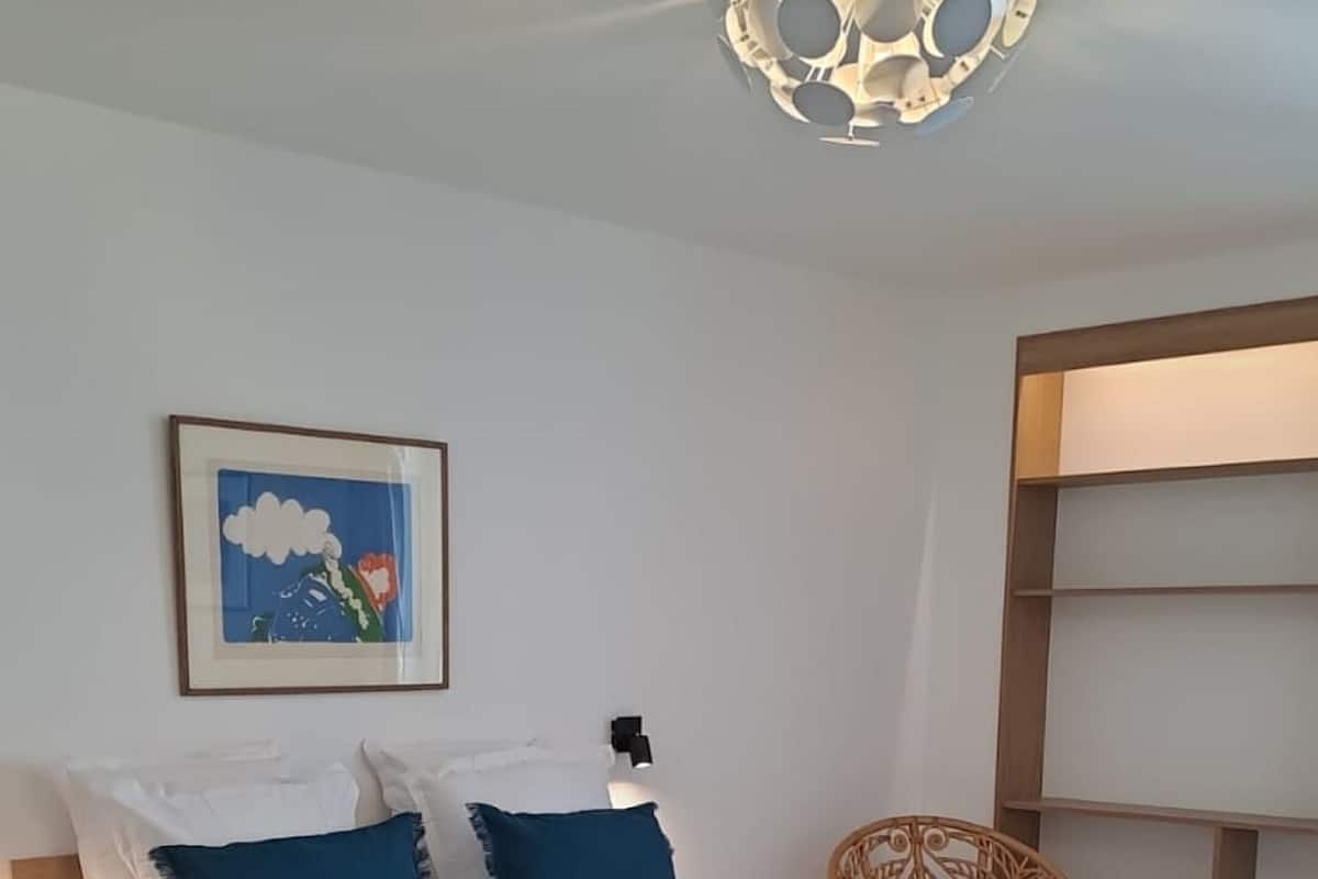 Una camera da letto con un letto, una sedia, un comodino e un punto luce a parete.