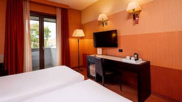 Habitació d'hotel amb dos llits, un escriptori, una cadira, un televisor i dues làmpades de paret.