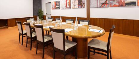 A conference room with a round table, chairs, and a projector screen.