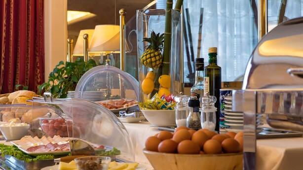 Una mesa de buffet con diversos alimentos, como carnes, quesos, frutas y huevos.