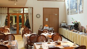 Een eetgedeelte met gedekte tafels, stoelen, een klok en een buffet.