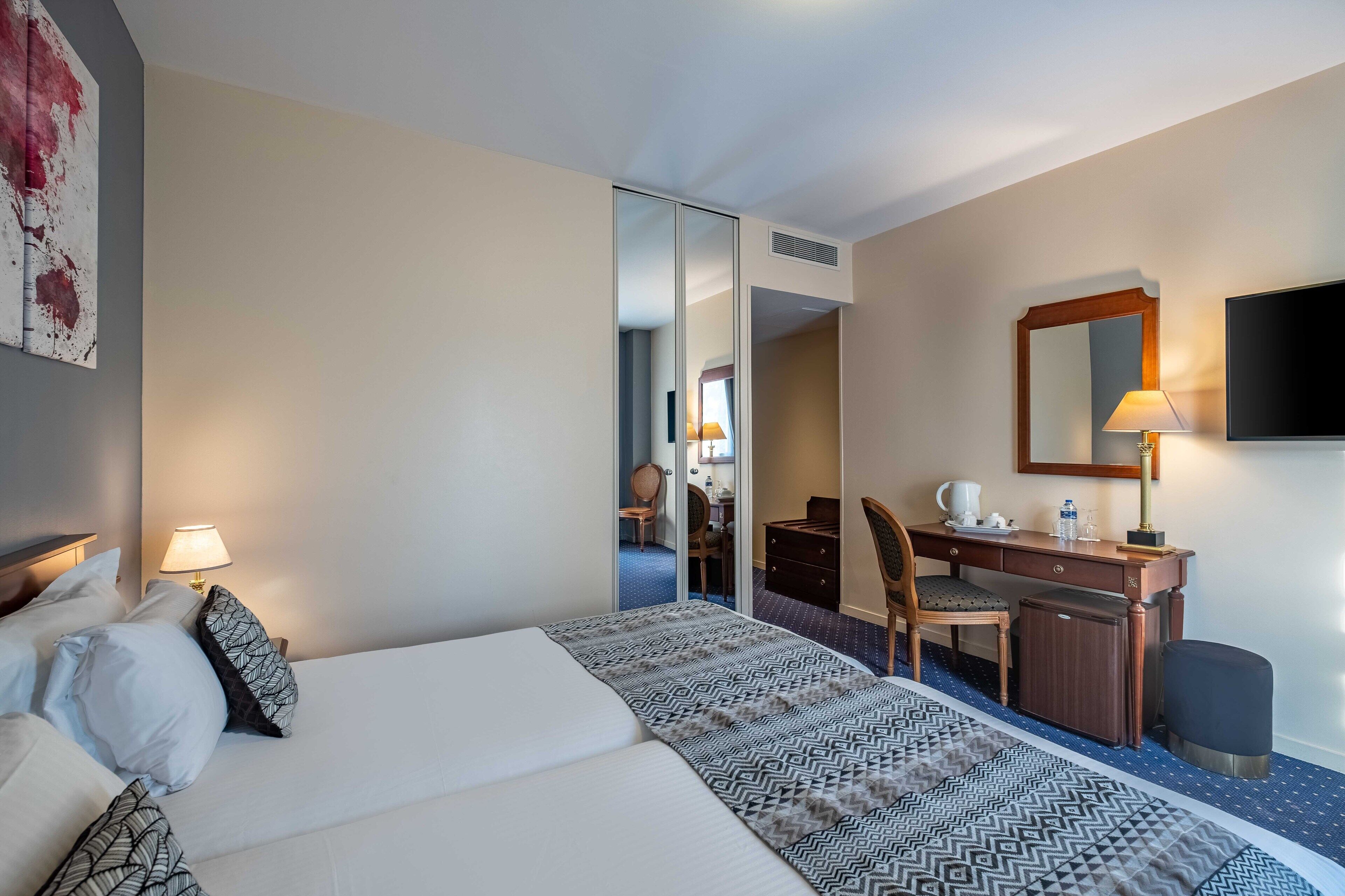 A hotel room with a bed, desk, chair, and a television.