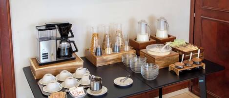 A breakfast buffet setup with coffee machines, glass containers, and serving dishes.