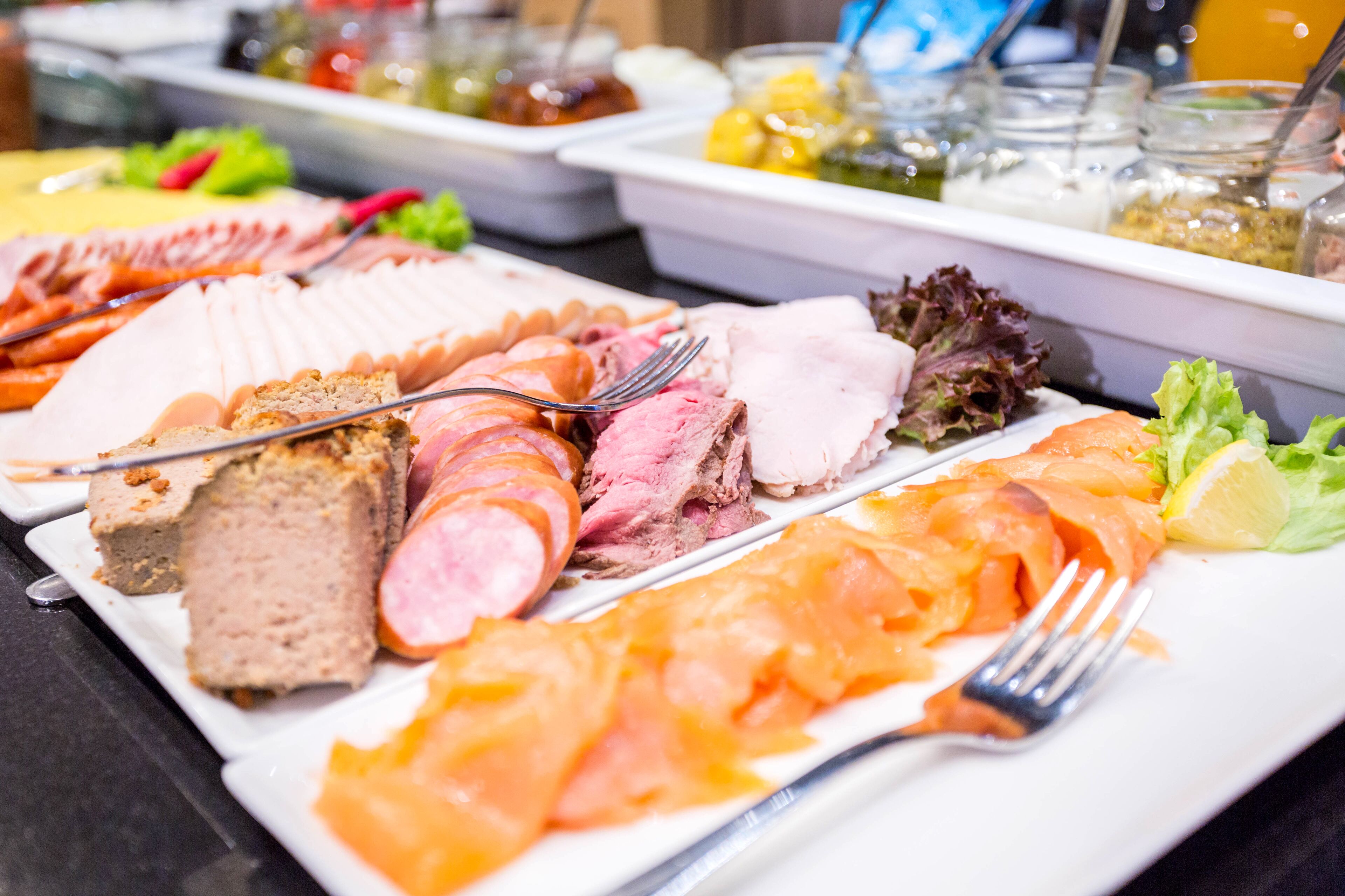 A buffet with various meats and salads.