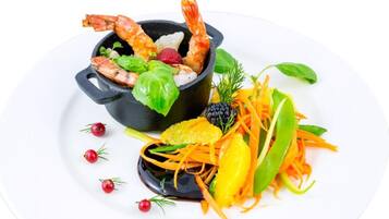 A dish with shrimp, vegetables, and a black bowl.