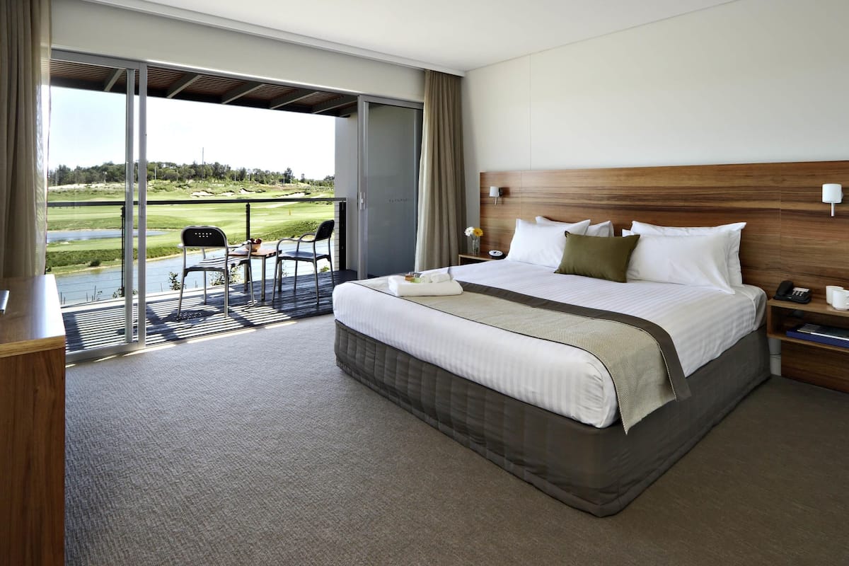 Une chambre d’hôtel avec un grand lit, un bureau et une vue sur un terrain de golf.