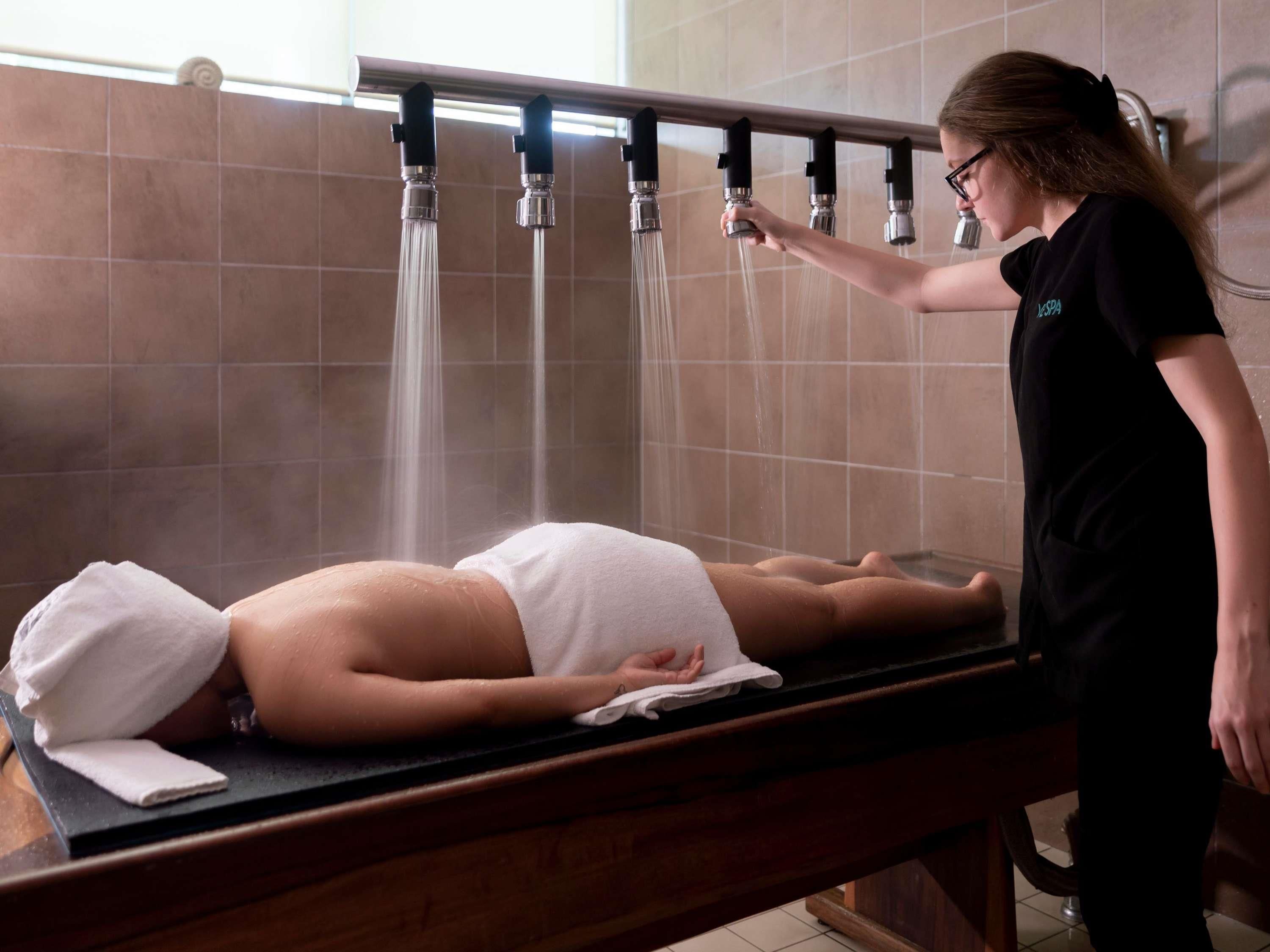 Una persona recostada en una camilla recibiendo una terapia con agua.