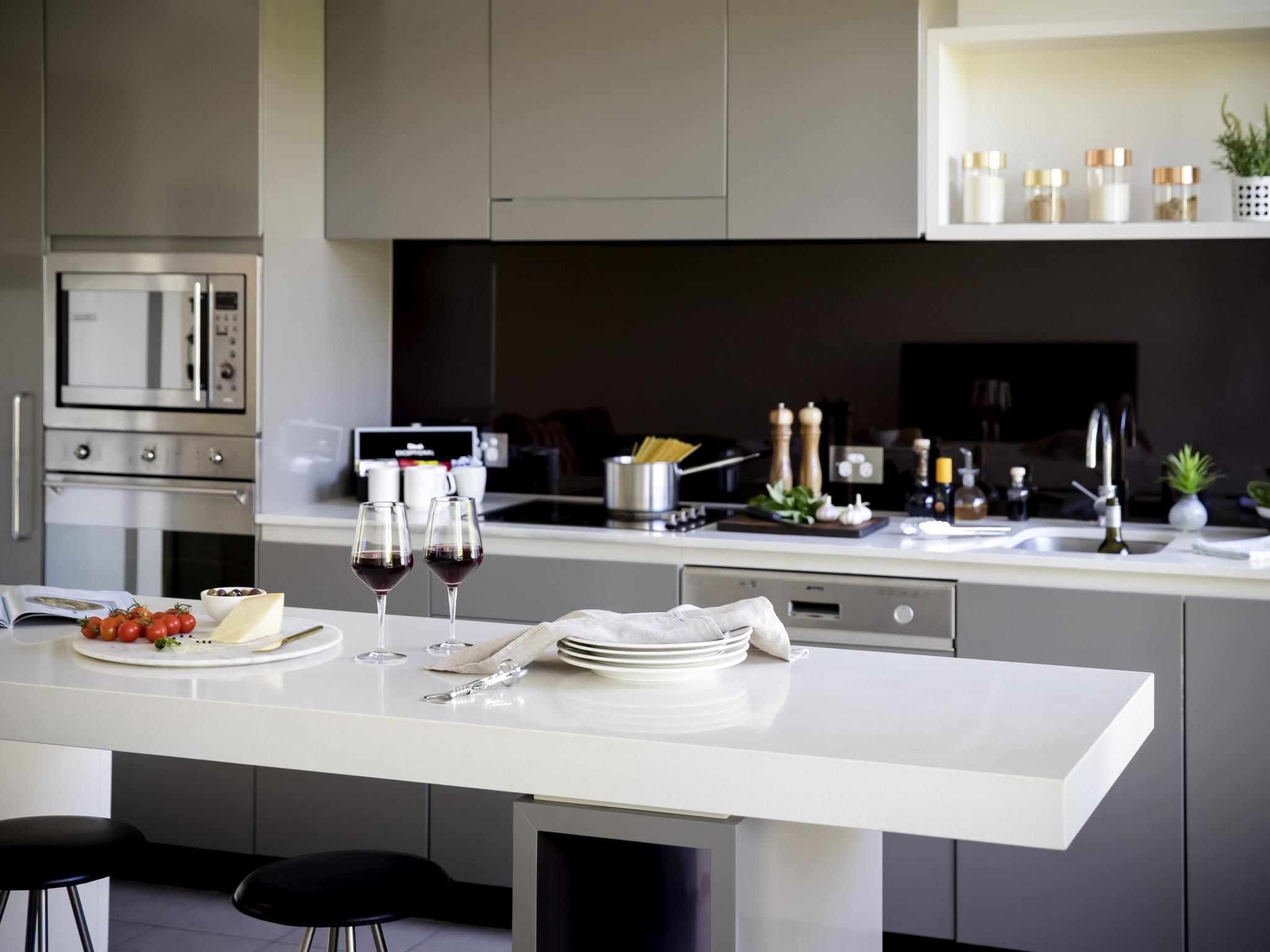 Una cocina moderna con encimera blanca, electrodomésticos de acero inoxidable y horno empotrado.