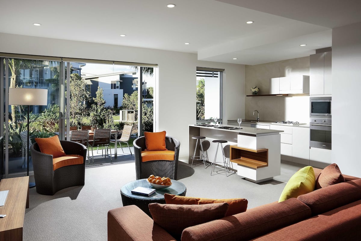 Un espace de vie moderne comprenant une cuisine, un coin repas et un balcon offrant une vue sur la ville.