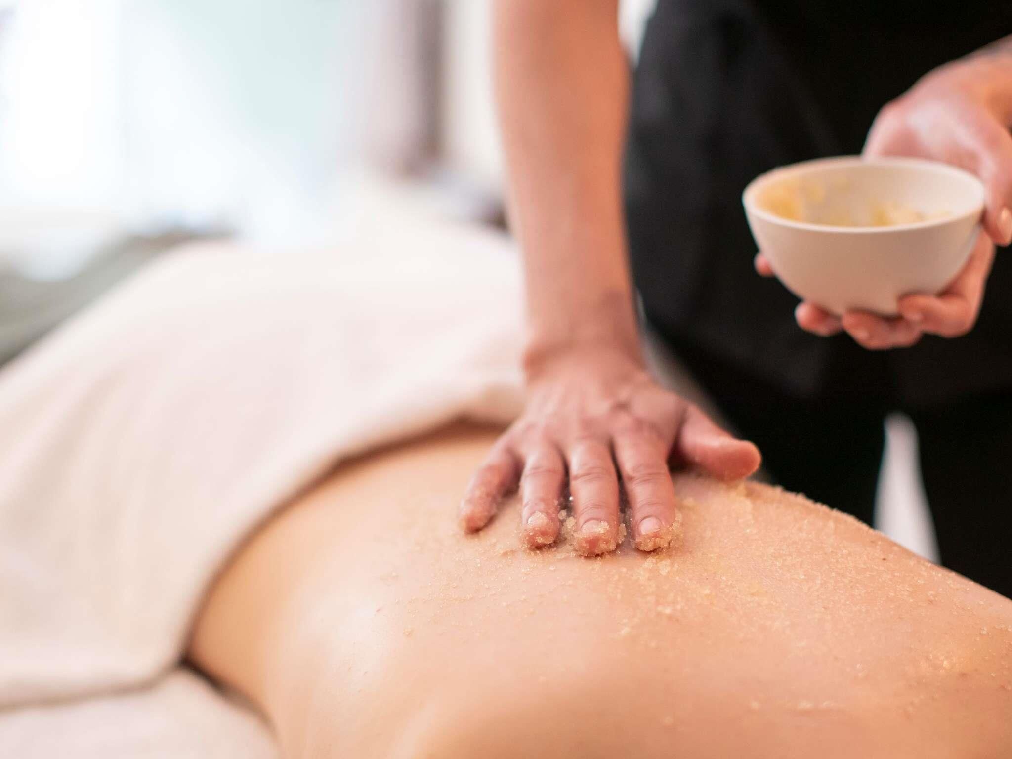 A person receiving a massage with a bowl of oil on their back.