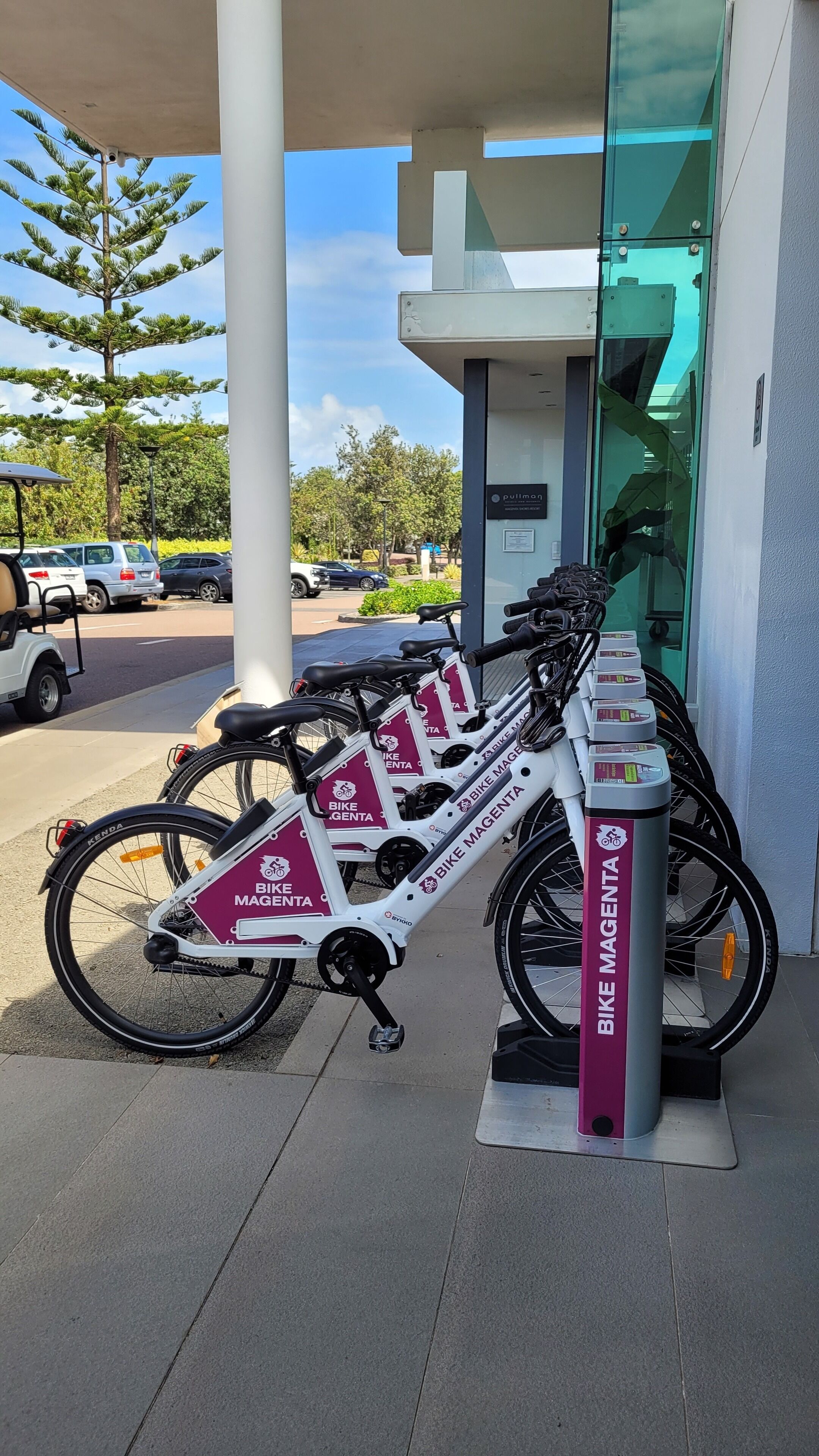 A bike rental station with multiple bikes and a sign for 'Bike Magenta'.
