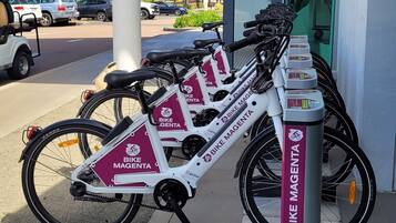 A bike rental station with multiple bikes and a sign for 'Bike Magenta'.