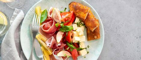 A plate with various foods and a glass of white wine.