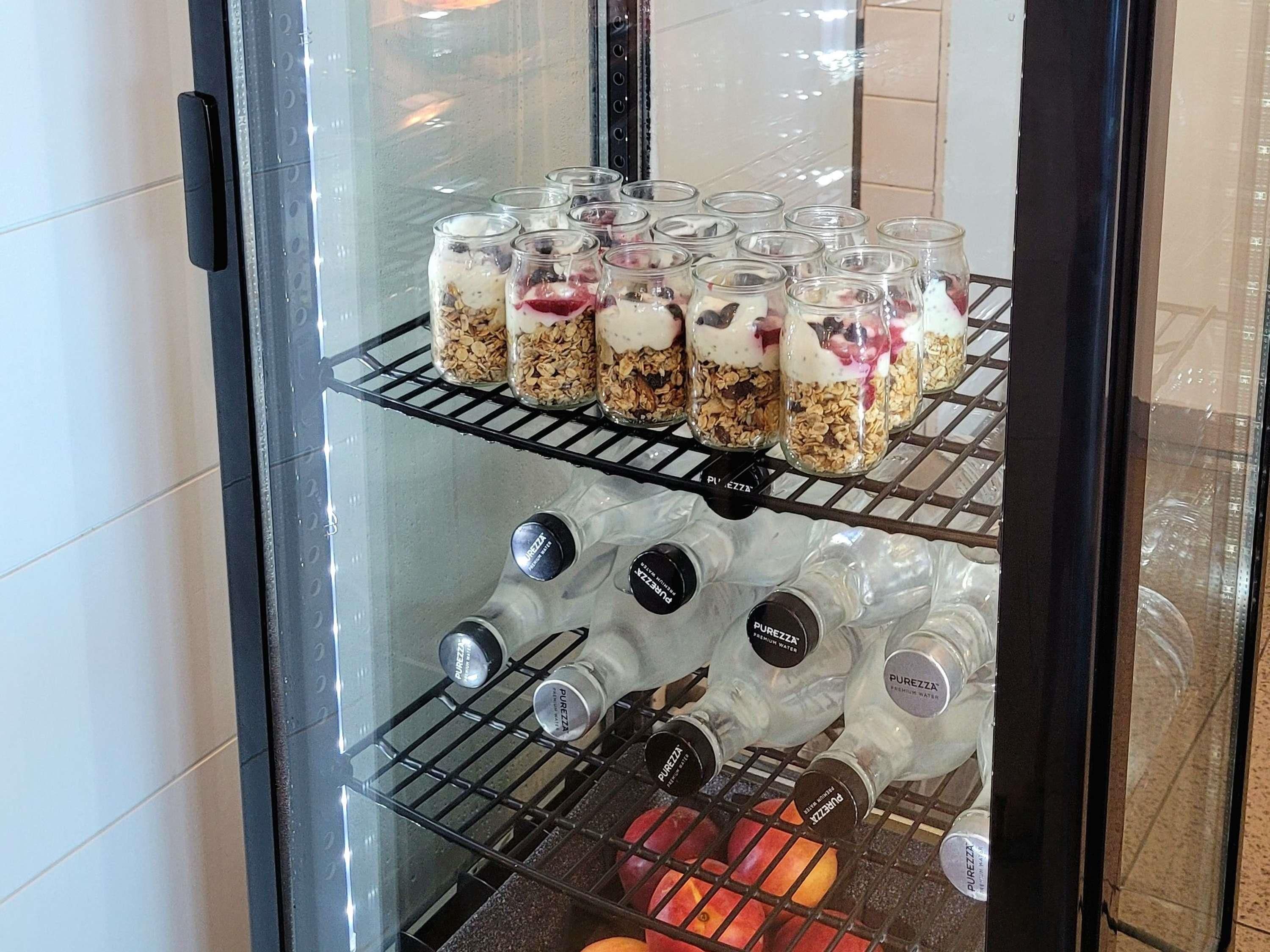A refrigerated display case with jars of layered food items and bottles of water.
