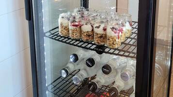 A refrigerated display case with jars of layered food items and bottles of water.