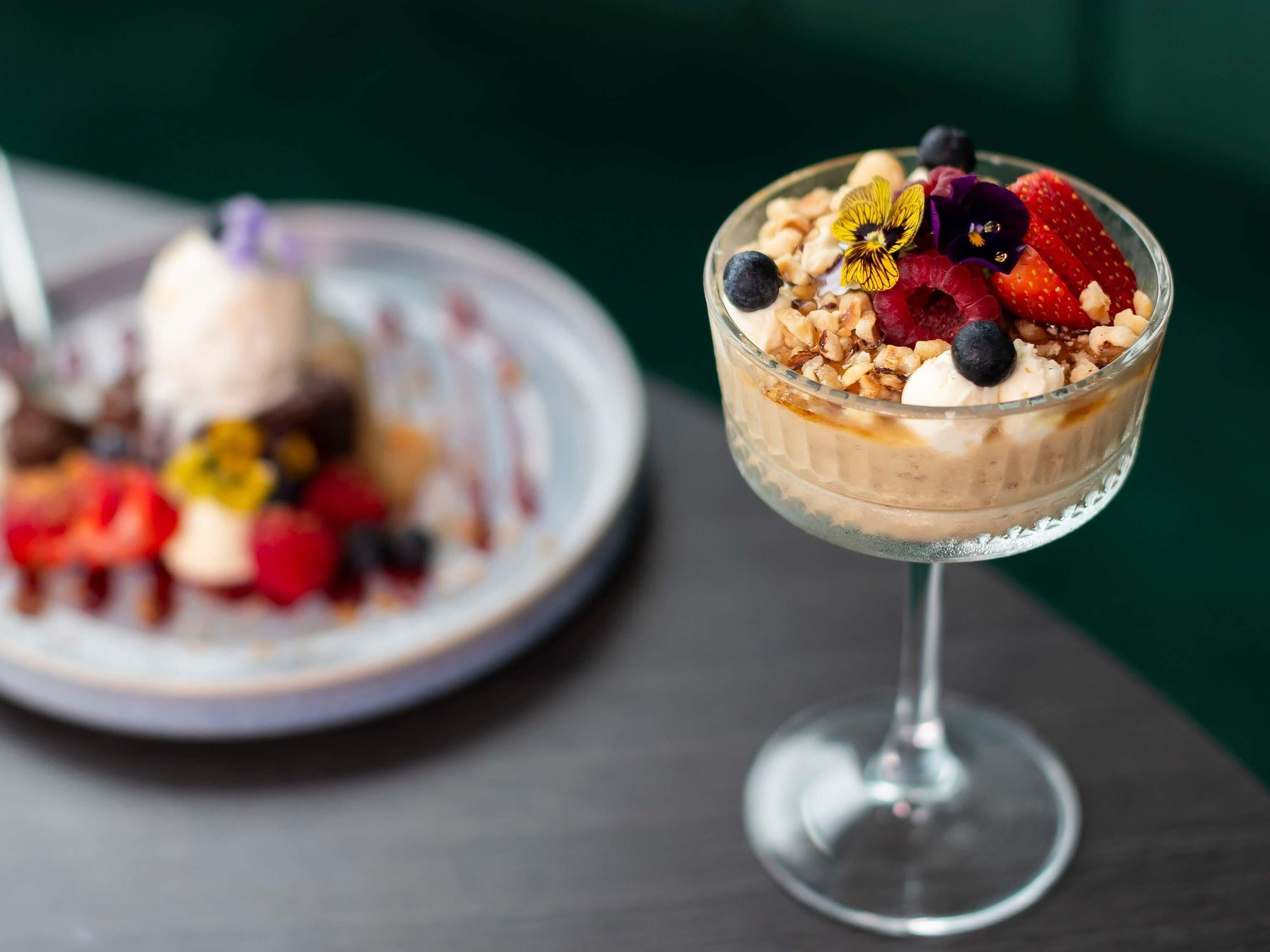 Postre en un bol de cristal con frutas y frutos secos sobre una mesa.