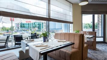 Un restaurante con una mesa preparada para dos, un sofá y vistas a la ciudad.