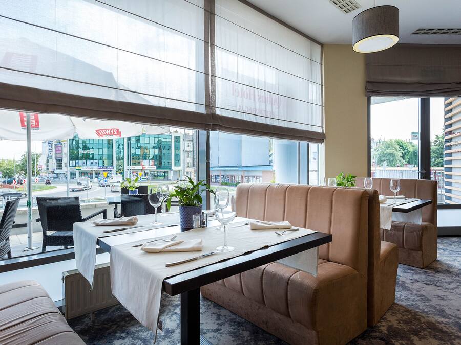 Un restaurante con una mesa preparada para dos, un sofá y vistas a la ciudad.