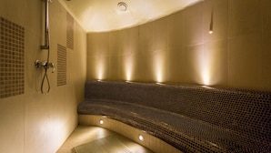 A modern spa with a curved seating area, a showerhead, and a tiled wall. - Qubus Hotel Kielce (Kielce)