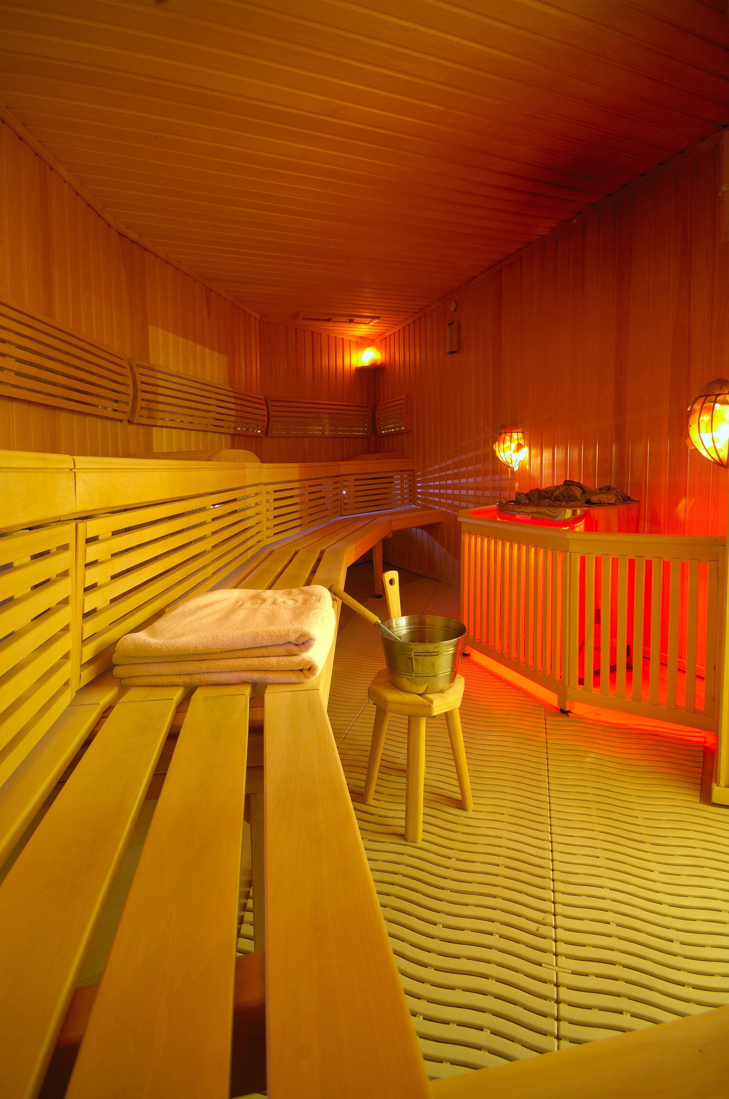 Een sauna met houten banken, een bank met een handdoek en een emmer.