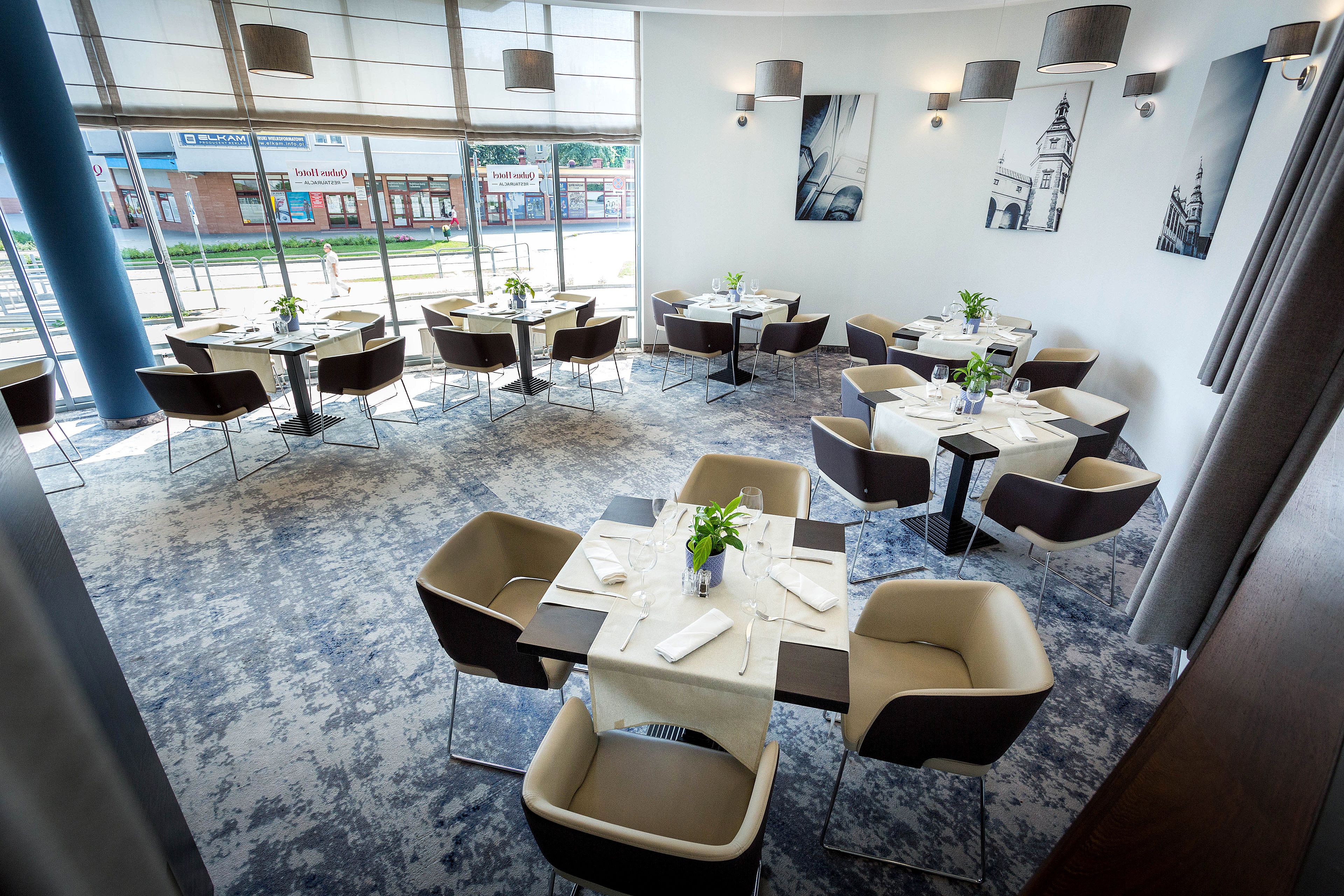Un restaurante moderno con mesas redondas, sillas negras y un piso con diseño azul.