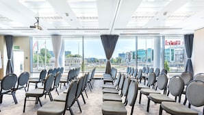 A conference room with rows of chairs facing a large window with a city view. - Qubus Hotel Kielce (Kielce)