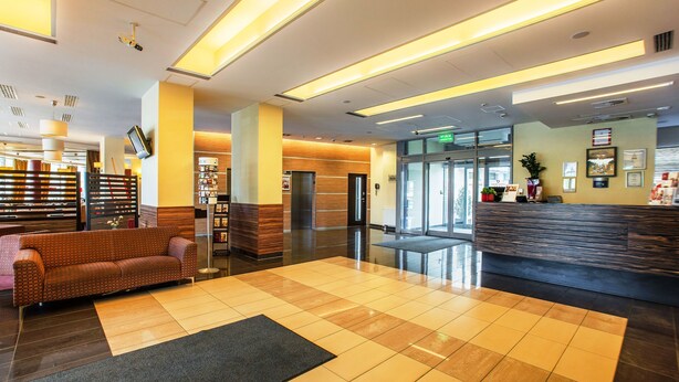A modern lobby with a check-in counter, a reception desk, a sofa, and a coffee machine. - Qubus Hotel Kielce (Kielce)