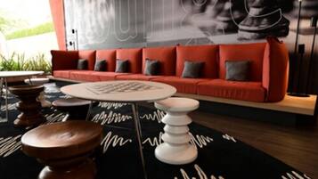 Uma sala de estar moderna com um sofá vermelho, uma mesa de centro branca e banquetas de madeira.