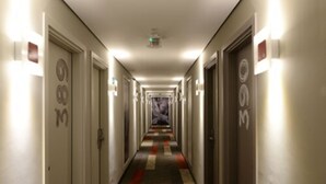 A hotel corridor with doors marked with room numbers, a patterned carpet, and wall-mounted light fixtures. - ibis Campo Grande (Campo Grande)