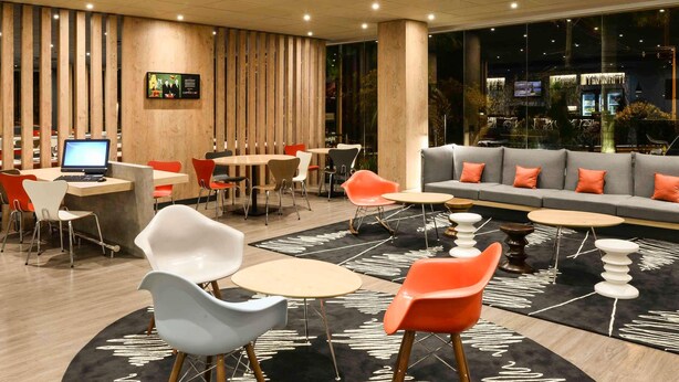 A modern lounge area with round tables, chairs, and a sofa. - ibis Campo Grande (Campo Grande)