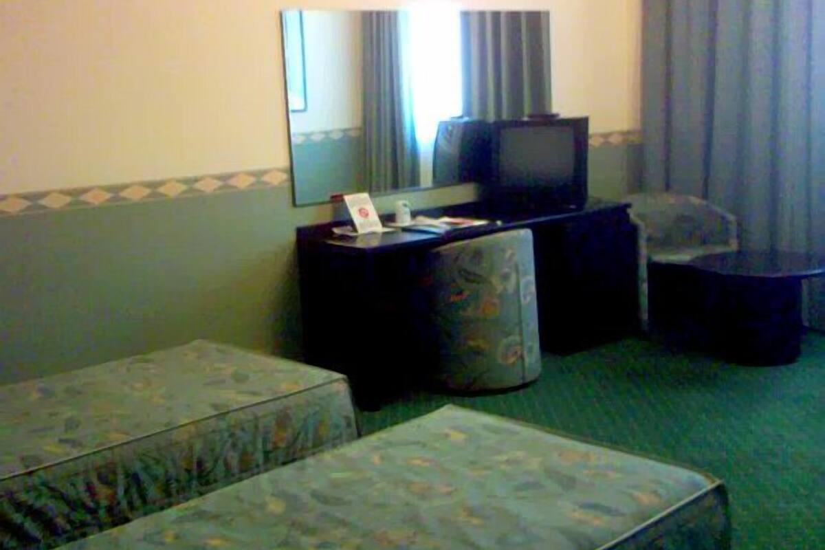 A hotel room with two upholstered sofas, a small table with a television, and a mirror on the wall.