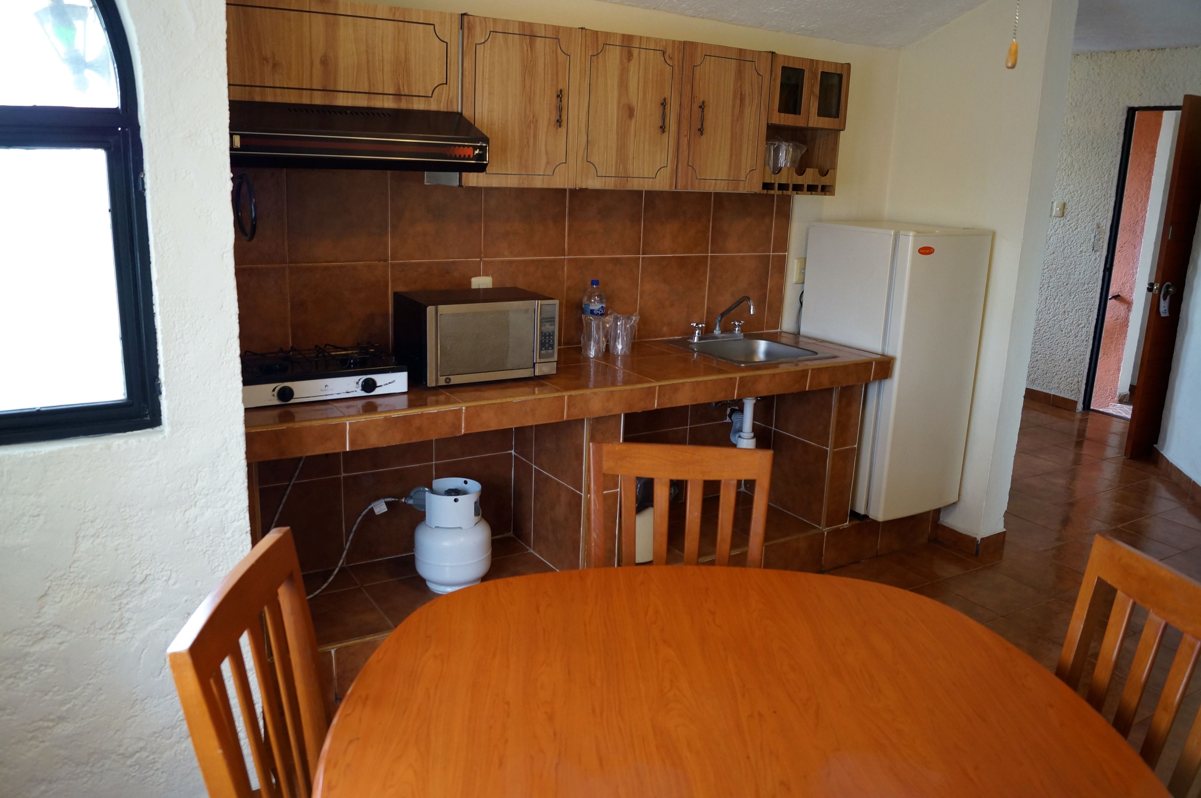 A kitchen with wooden cabinets, a microwave, a gas stove, a sink, and a refrigerator.