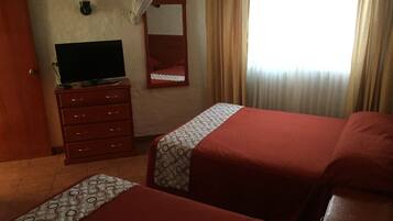 Habitación de hotel con dos camas, un televisor en una cómoda, un espejo y una ventana con cortinas.
