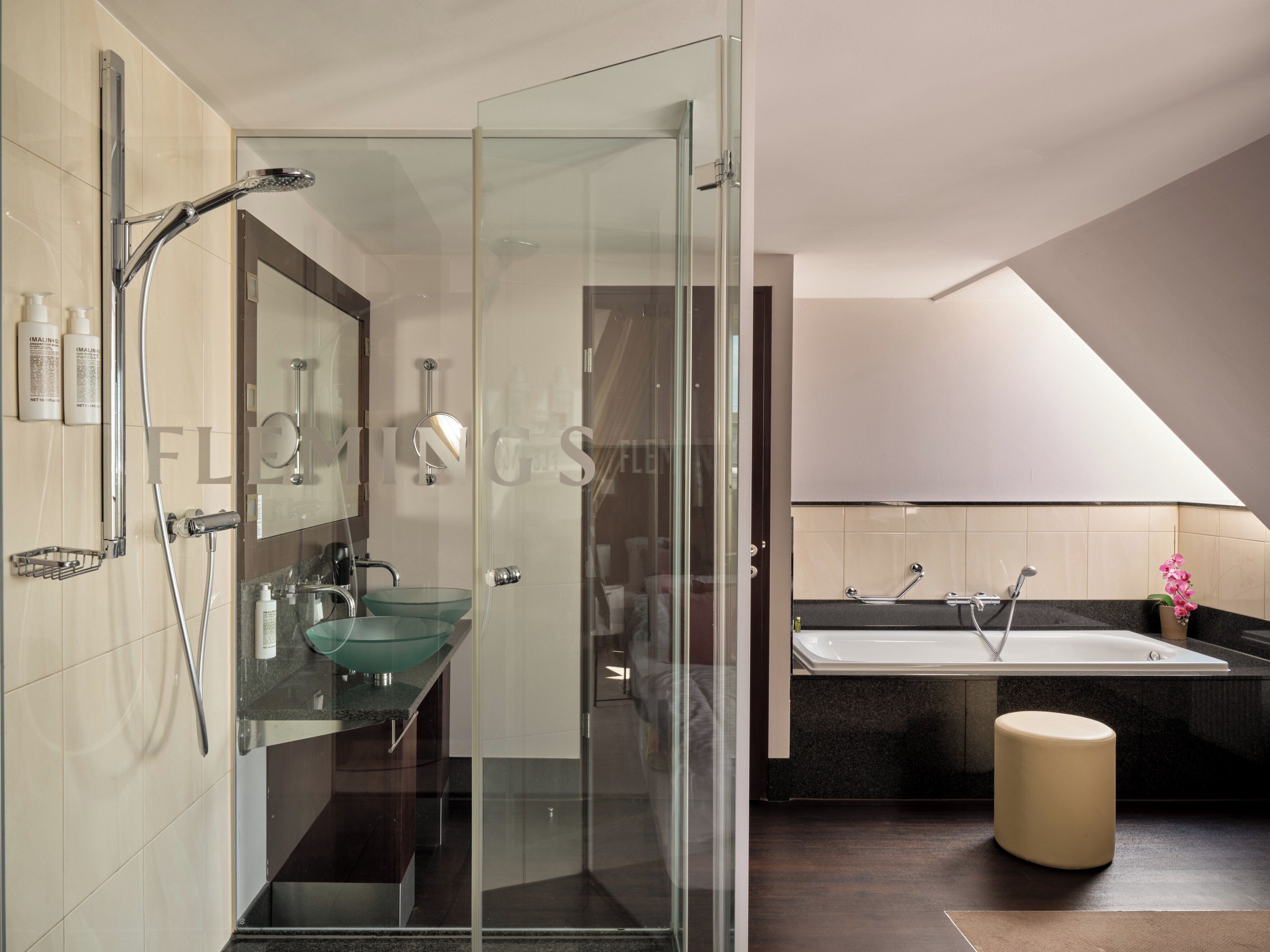 Une salle de bain moderne avec une douche à parois de verre, un lavabo en verre, une baignoire et des toilettes.