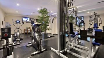 Un gimnasio con diversos equipos de ejercicio, una cinta de correr y un espejo grande.