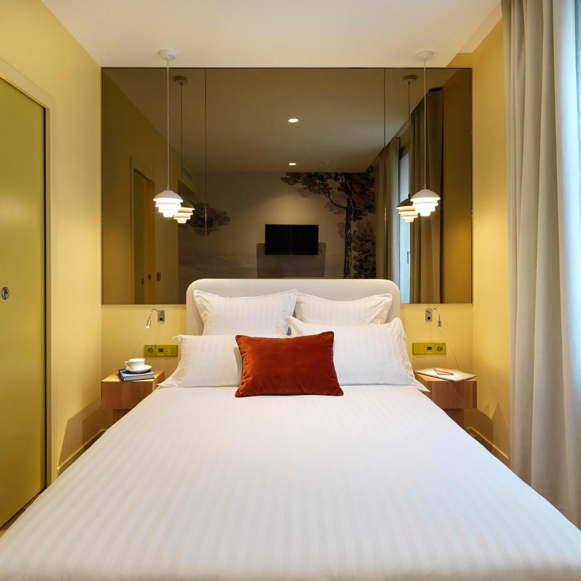 A hotel room with a large bed, two bedside tables, a flat-screen TV, and a decorative wall piece.