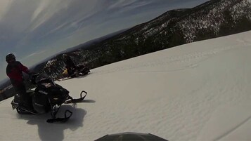 Una persona conduciendo un vehículo de nieve sobre una ladera nevada.