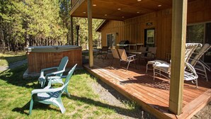 A wooden deck with outdoor seating, a grill, and a hot tub. - DiamondStone Guest Lodges (La Pine)