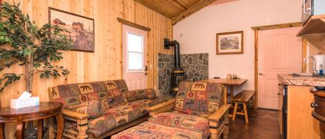 L’intérieur d’un chalet confortable, avec un plafond en bois, une cheminée en pierre, une table à manger en bois et un ensemble de canapés.