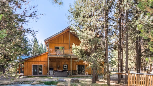 A wooden cabin with a balcony, a deck, and a small outdoor kitchen area. - DiamondStone Guest Lodges (La Pine)