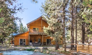 A wooden cabin with a balcony, a deck, and a small outdoor kitchen area.