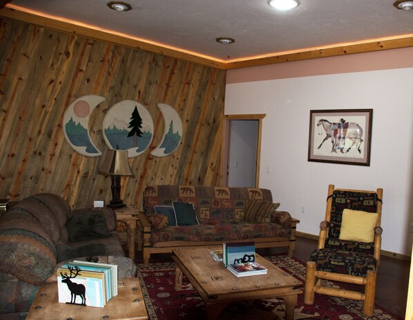 A cozy living room with a wooden wall, a sofa, a chair, and a coffee table.