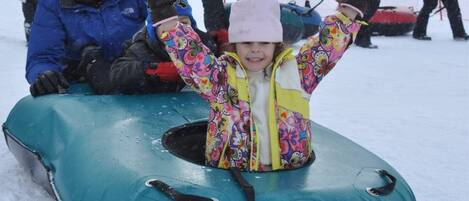A child in a colorful jacket on a snow tube.