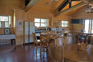 A wooden cabin kitchen with a refrigerator, stove, and dining table. - DiamondStone Guest Lodges (La Pine)