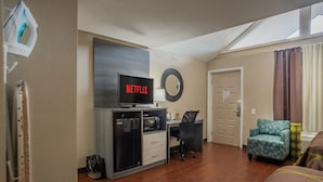 A hotel room with a desk, a chair, a bed, a TV displaying 'NETFLIX', a microwave, and a small trash bin. - Super 8 by Wyndham Downtown Gatlinburg at Convention Center (Gatlinburg)