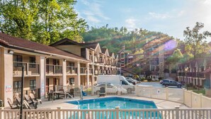 A hotel with a pool, outdoor seating, and a view of the surrounding hills. - Super 8 by Wyndham Downtown Gatlinburg at Convention Center (Gatlinburg)