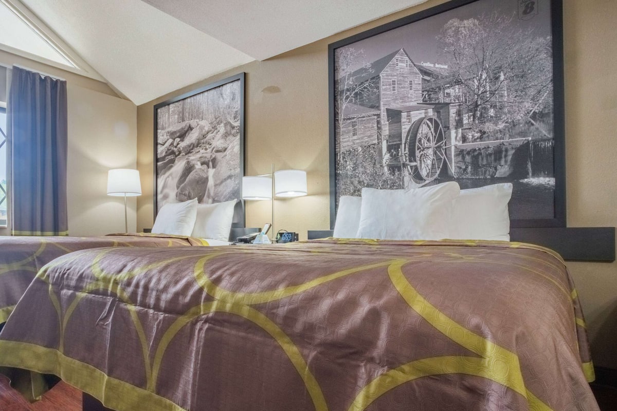 A hotel room with a large bed, two bedside lamps, and two framed pictures on the wall.