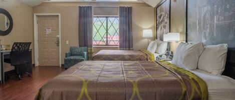 A hotel room with a large bed, a desk, a chair, and a window with curtains.