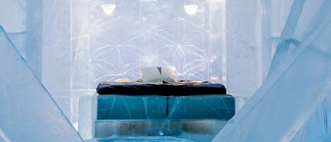 Una habitación de hotel de hielo con cama, ventana y lámparas colgantes.
